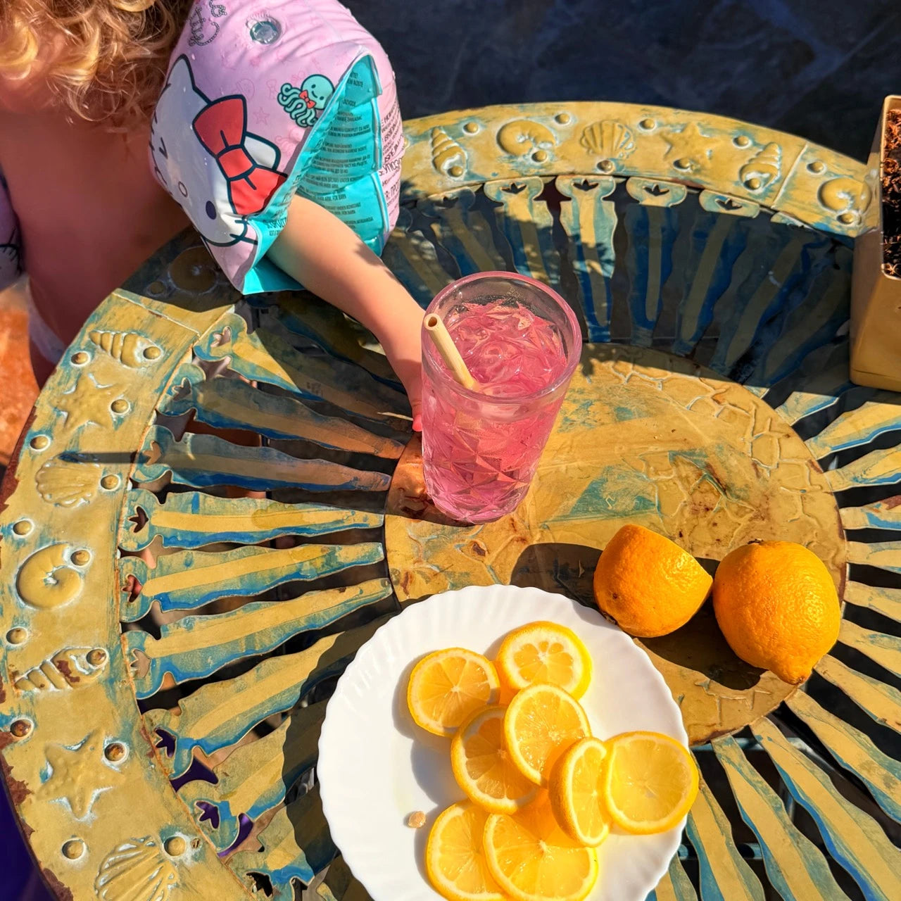 Jenna’s daughter wearing swimming armbands with a pink drink at the table